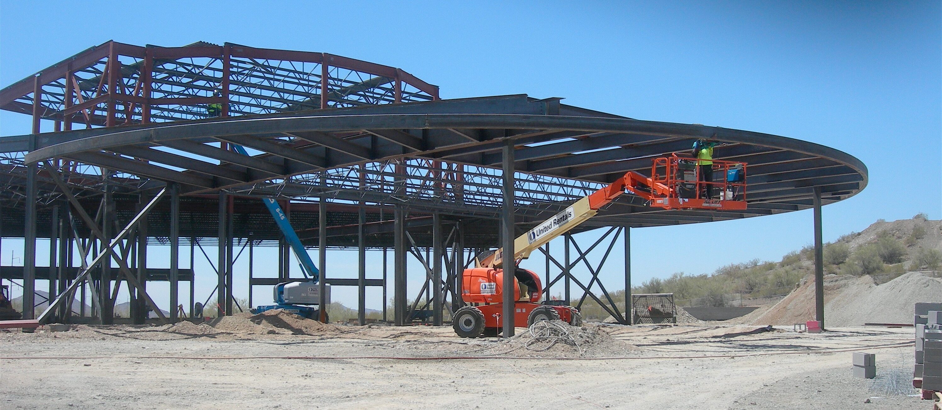 A crane is lifting up the roof of an industrial building.