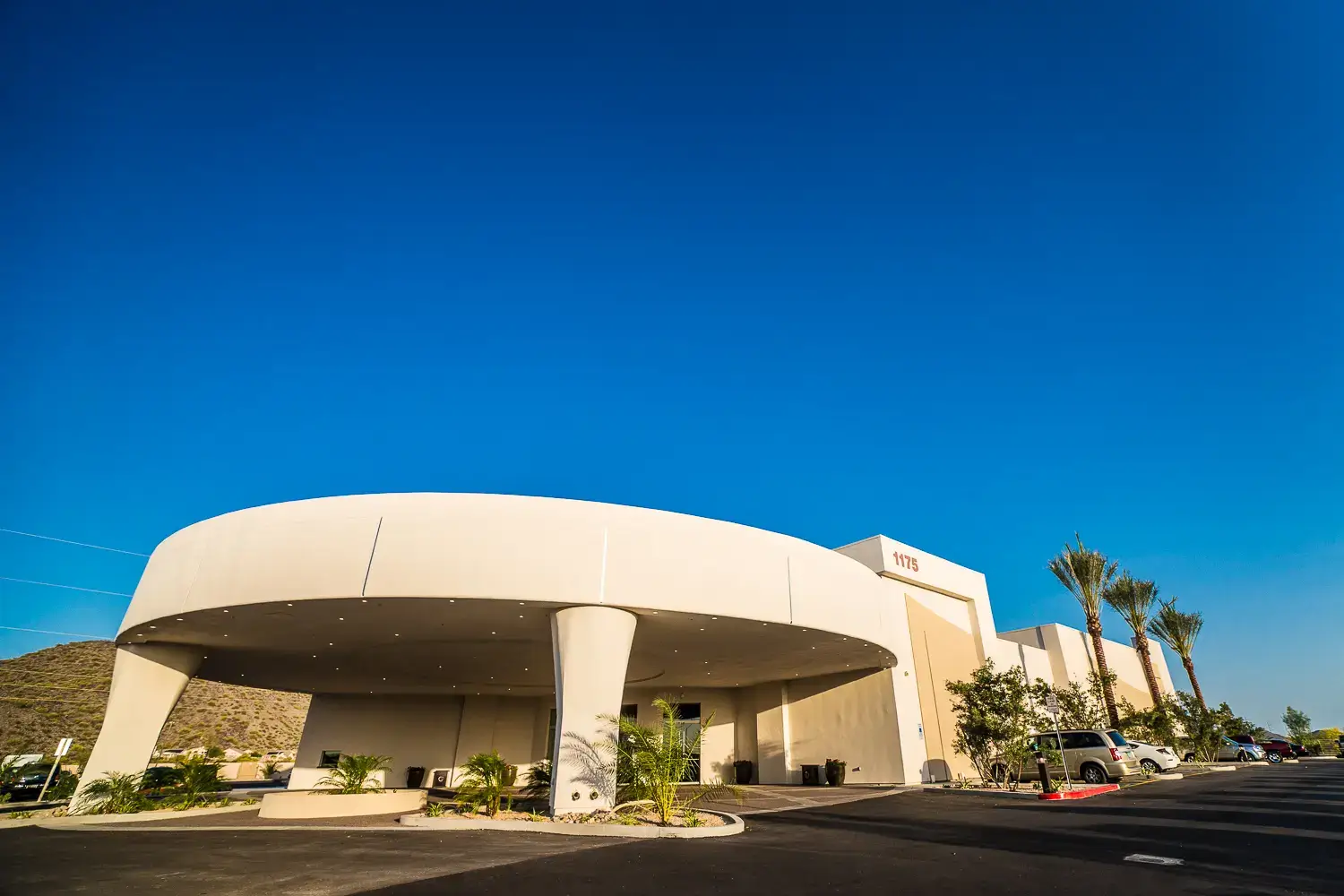 A large white building with palm trees in front of it.
